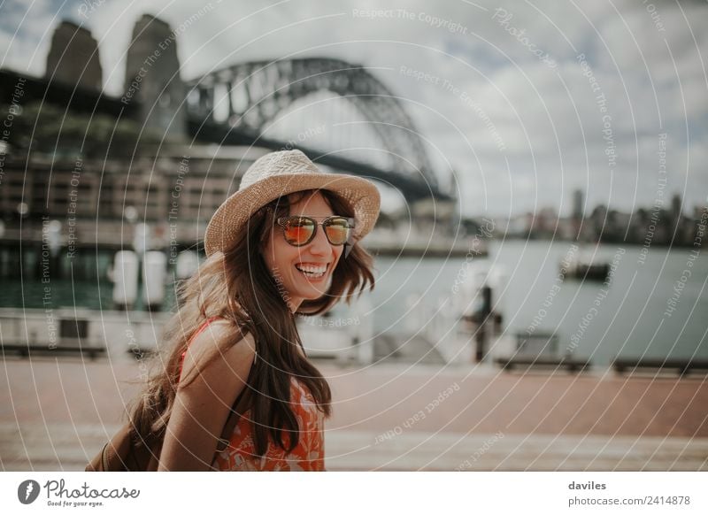 Happy blonde woman with hat and sunglasses laughing in Sydney city Harbour, with Harbour Bridge in the background, in Australia. Lifestyle Style Joy