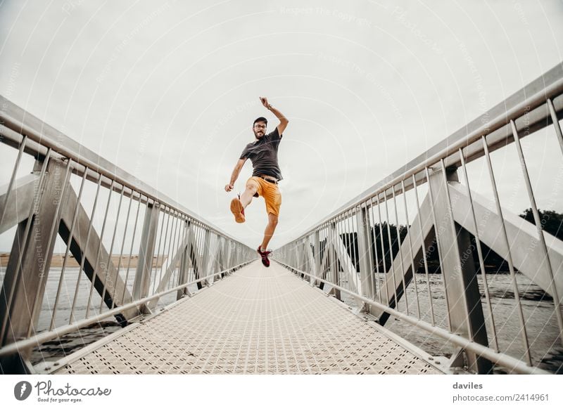 White man with shorts and t shirt jumping with energy on a bridge. Lifestyle Athletic Wellness Well-being Leisure and hobbies Vacation & Travel Adventure