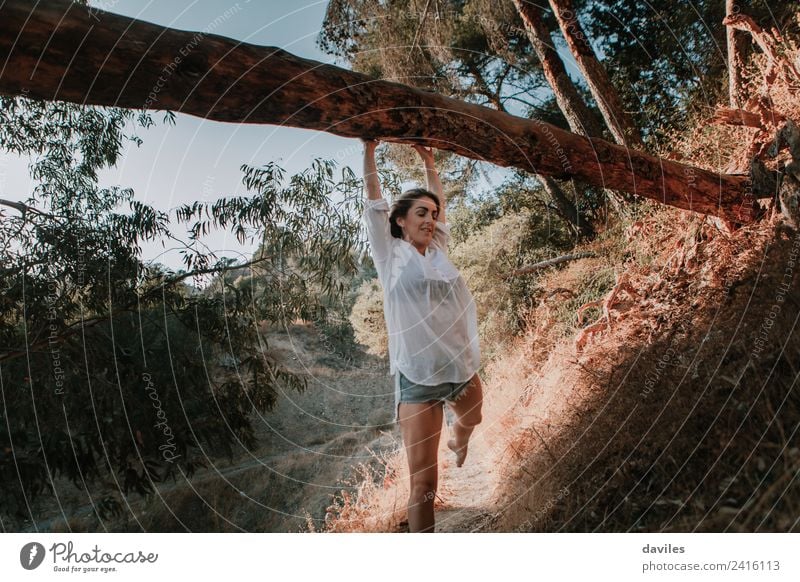 Smiling woman walking in nature and hanging from a fallen tree Lifestyle Mountain Hiking Human being Woman Adults 1 18 - 30 years Youth (Young adults) Nature