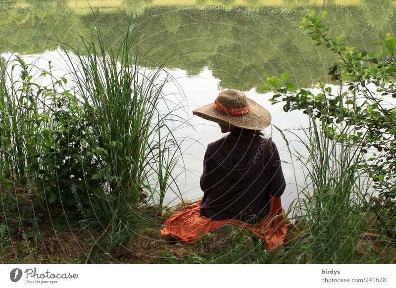 Woman with straw hat on the lakeside. Romantic scene Young woman Romance Happy Calm 1 Human being Water Summer Beautiful weather Lakeside To enjoy Sit Feminine