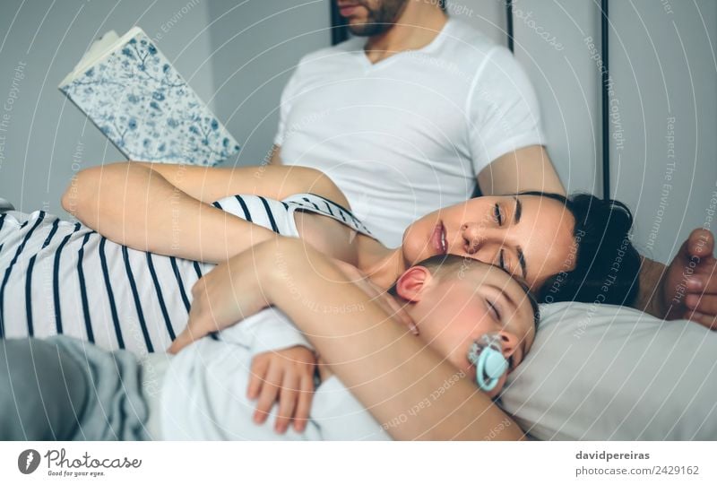 Man reading with wife and son sleeping Beautiful Relaxation Reading Bedroom Child Human being Baby Toddler Woman Adults Parents Mother Father Family & Relations