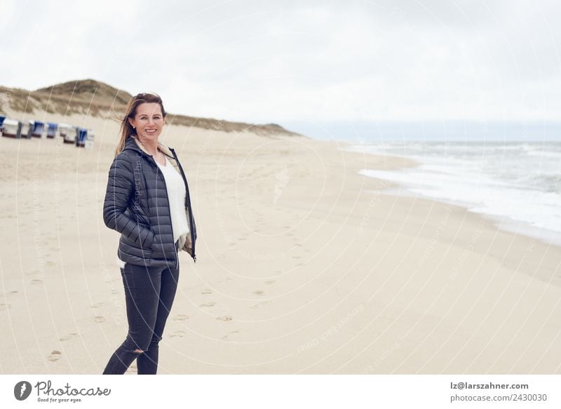 Woman walking on a beach on a cloudy day Leisure and hobbies Freedom Beach Ocean Adults 1 Human being 45 - 60 years Sand Clouds Autumn Coast North Sea