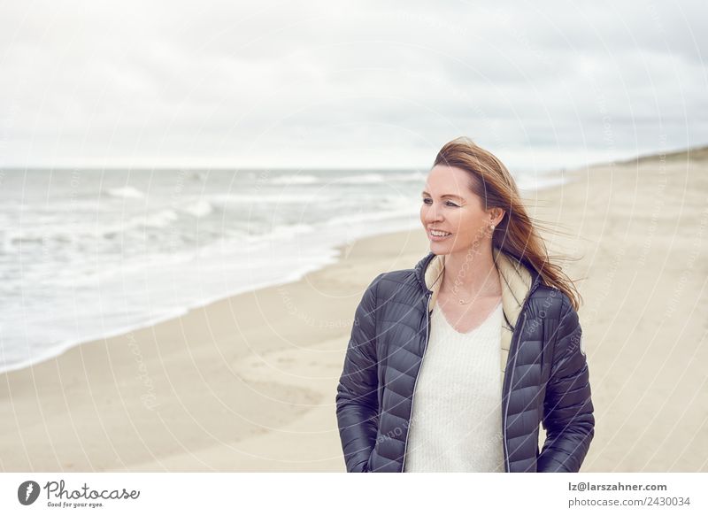 Woman walking on a beach on a cloudy day Leisure and hobbies Freedom Beach Ocean Adults 1 Human being 45 - 60 years Sand Clouds Autumn Coast North Sea