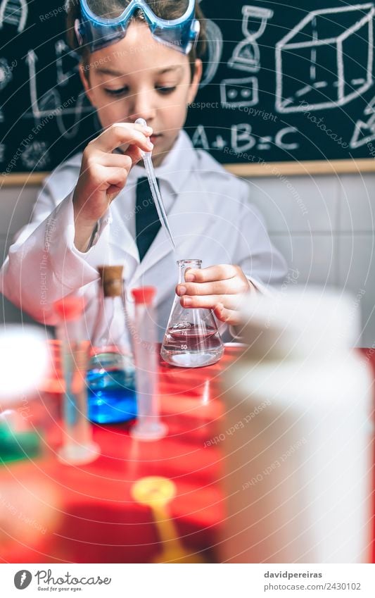 Serious kid playing with chemical liquids Bottle Happy Playing Flat (apartment) Table Science & Research Child Classroom Blackboard Laboratory Human being