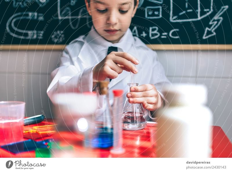 Serious kid playing with chemical liquids Bottle Happy Playing Flat (apartment) Table Science & Research Child Classroom Blackboard Laboratory Human being