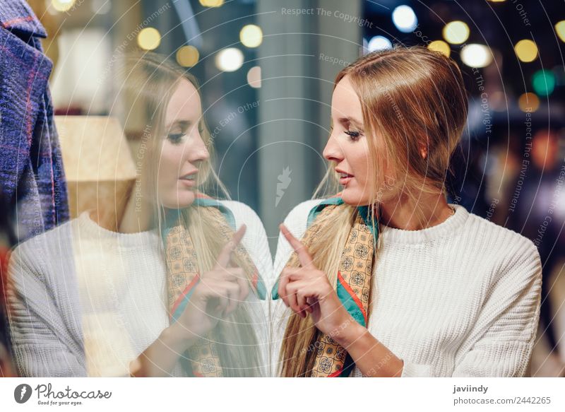 Blonde girl wearing white sweater standing in the street with defocused city lights at the background. Lifestyle Shopping Style Happy Beautiful