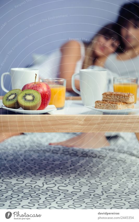 Healthy breakfast on tray and couple lying in background Fruit Apple Breakfast Juice Coffee Lifestyle Happy Beautiful Relaxation Leisure and hobbies Bedroom