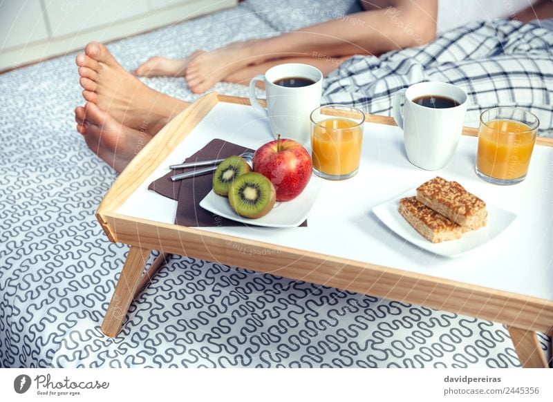 Healthy breakfast on tray and couple legs in background Fruit Apple Breakfast Juice Coffee Lifestyle Happy Relaxation Leisure and hobbies Bedroom Woman Adults