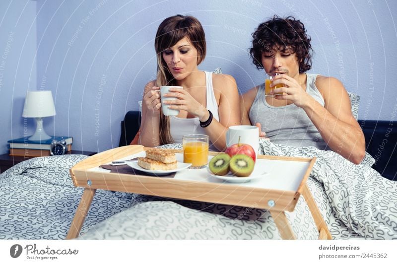 Couple having breakfast in bed served over tray Fruit Apple Breakfast Juice Coffee Lifestyle Happy Beautiful Relaxation Leisure and hobbies Bedroom Woman Adults