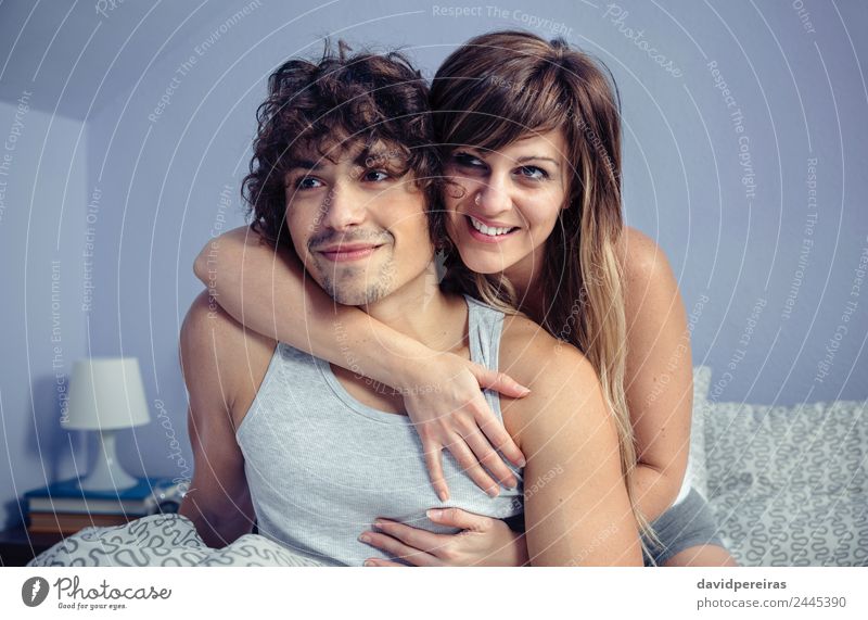 Couple in love embracing and smiling sitting over bed Lifestyle Happy Beautiful Relaxation Bedroom Camera Woman Adults Man Family & Relations Smiling Laughter