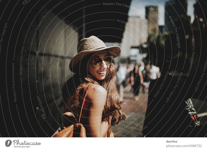 Happy woman in sunglasses and hat walking by Sydney city streets, and looking back to the camera. Lifestyle Shopping Style Leisure and hobbies Vacation & Travel