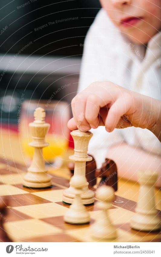 Boy of primary school age plays chess Joy Leisure and hobbies Playing Chess Flat (apartment) Room Think Schoolchild Chessboard Boy (child) Colour photo