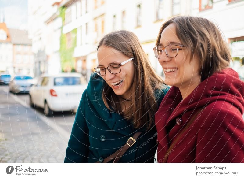 two sisters laugh heartily on the street Lifestyle Joy luck Human being Feminine Young woman Youth (Young adults) Brothers and sisters Sister 2