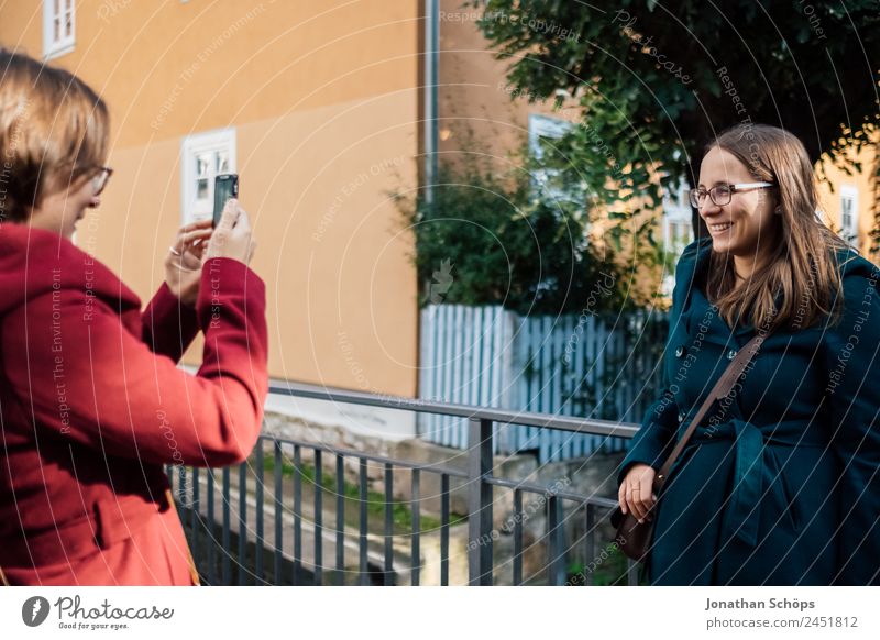 Twin sisters take pictures of each other with smartphone at a bridge railing Lifestyle Style Joy luck Human being Feminine Young woman Youth (Young adults)