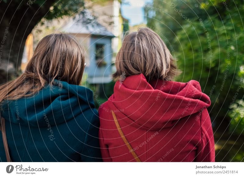 Twin sisters sitting with their backs to the camera Lifestyle Style Joy luck Human being Feminine Young woman Youth (Young adults) Brothers and sisters Sister 2