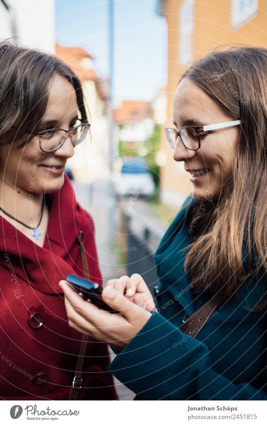 Twin sisters looking at a smartphone together Lifestyle Style Joy luck Human being Feminine Young woman Youth (Young adults) Brothers and sisters Sister 2