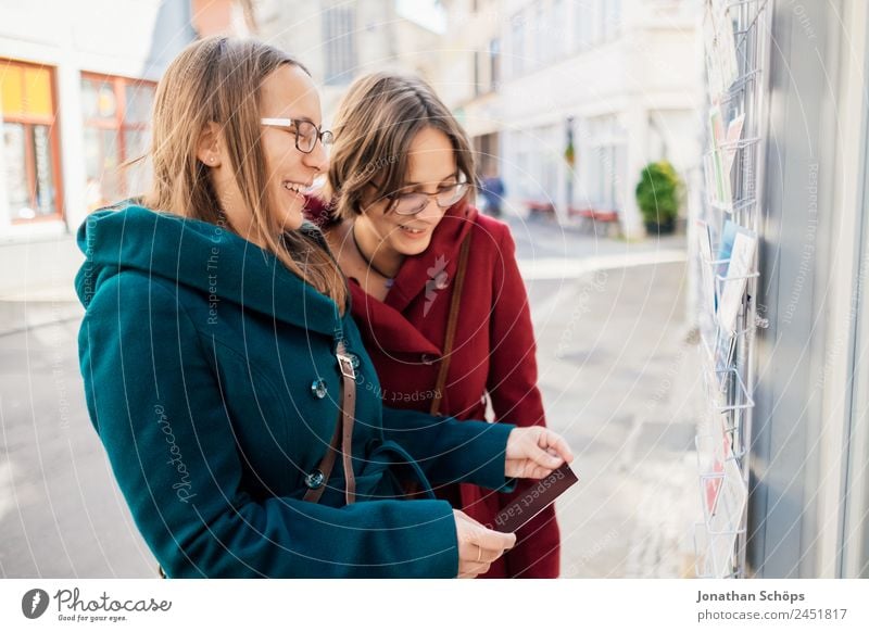 Twin sisters laughing at a postcard in Erfurt Lifestyle Joy luck Human being Feminine Young woman Youth (Young adults) Brothers and sisters Sister 2