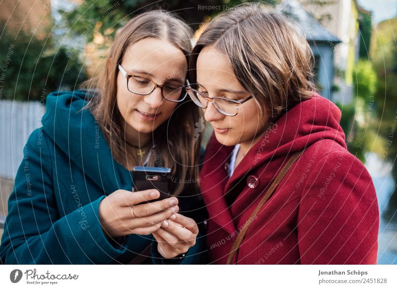 Twin sisters looking at a smartphone together Lifestyle Style Joy luck Human being Feminine Young woman Youth (Young adults) Brothers and sisters Sister 2