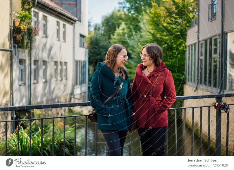 happy twin sisters stand facing each other on a bridge Lifestyle Style Joy luck Human being Feminine Young woman Youth (Young adults) Brothers and sisters