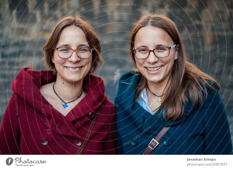 laughing twin sisters in front of the wall with red and blue green coat Lifestyle Style Joy luck Human being Feminine Young woman Youth (Young adults)