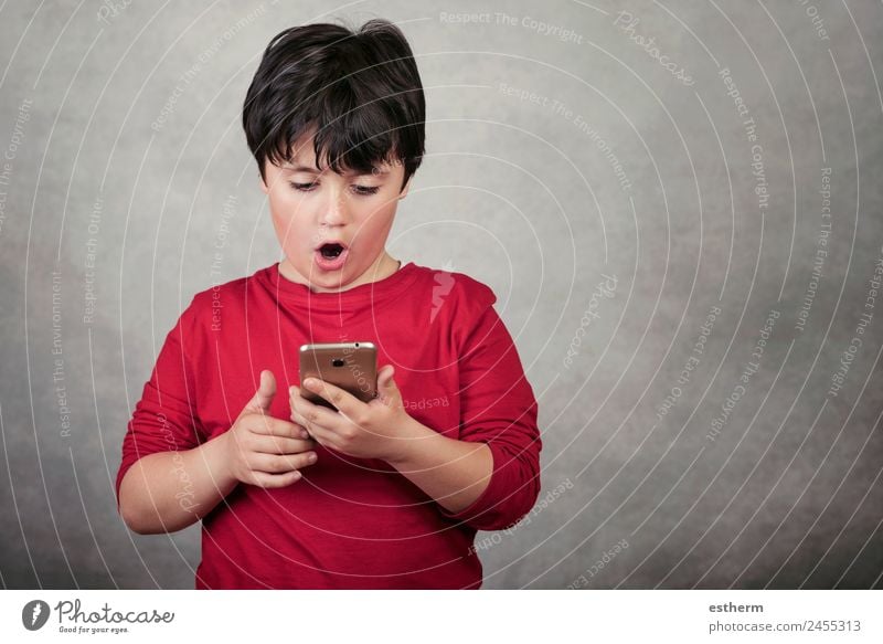 surprised child with a mobile phone on gray background Lifestyle Playing Telephone Cellphone Screen Technology Entertainment electronics Internet Masculine