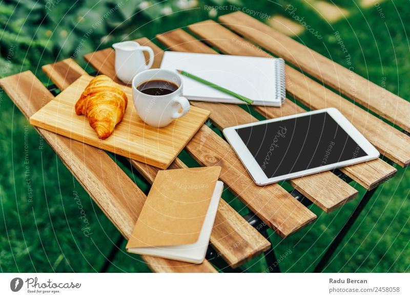 Morning Breakfast In Green Garden With French Croissant, Coffee Cup, Orange Juice, Tablet and Notes Book On Wooden Table Background picture Summer White Food