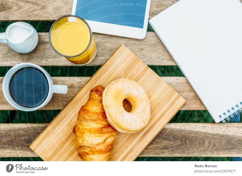 Morning Breakfast In Green Garden With French Croissant, Donuts, Coffee Cup, Orange Juice, Tablet and Notes Book On Wooden Table Background picture White Food