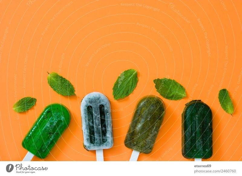 Green frozen popsicles on orange background. Top view. Copyspace Food Fruit Ice cream Summer Summer vacation Exotic Cold Frozen foods Herbs Sweet Dessert