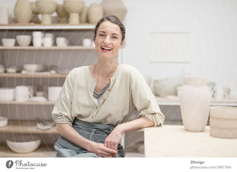 Woman in work wear in her workshop by table with handmade items Crockery Lifestyle Leisure and hobbies Handcrafts Table Work and employment Profession