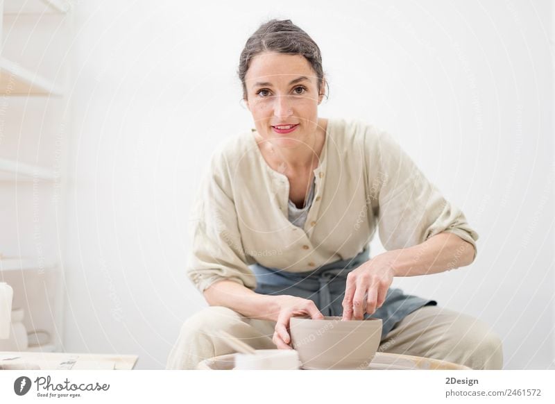 Young female sitting by table and making clay or ceramic mug in her working studio Crockery Lifestyle Leisure and hobbies Handcrafts Table Work and employment