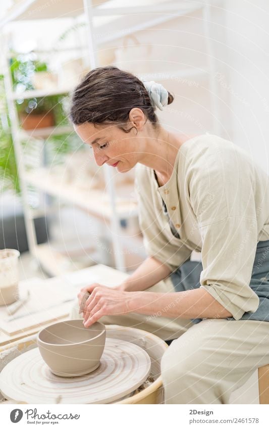 Young female sitting by table and making clay or ceramic mug Crockery Leisure and hobbies Handcrafts Table Work and employment Profession Craftsperson Workplace