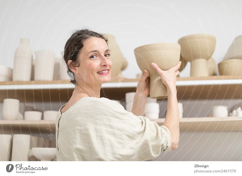 Beautiful ceramist owner looking to the camera while smiling Pot Leisure and hobbies Handcrafts Work and employment Profession Craftsperson Workplace Office