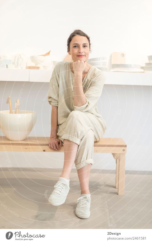 Woman in work wear in her workshop by table with handmade items Crockery Lifestyle Leisure and hobbies Handcrafts Table Work and employment Profession