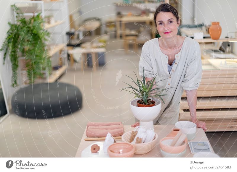 Woman in work wear in her workshop by table with handmade items Crockery Lifestyle Elegant Leisure and hobbies Handcrafts Table Work and employment Profession