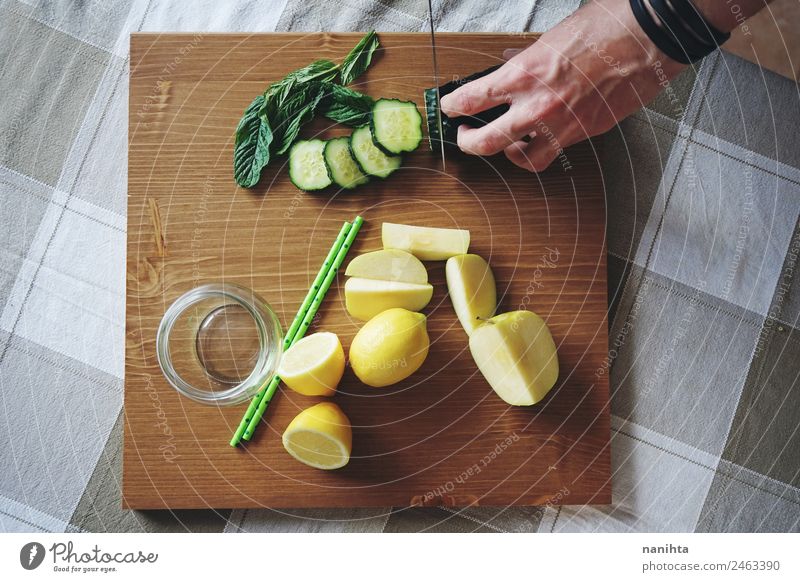 Man cutting fresh vegetables and fruits Food Vegetable Fruit Apple Herbs and spices Cucumber Mint leaf Lemon Slices of cucumber Nutrition Breakfast