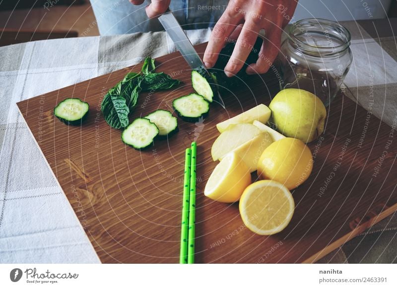 Young man making a smoothie with vegetables Food Fruit Apple Lemon Cucumber Mint Nutrition Eating Organic produce Vegetarian diet Diet Glass Straw Knives