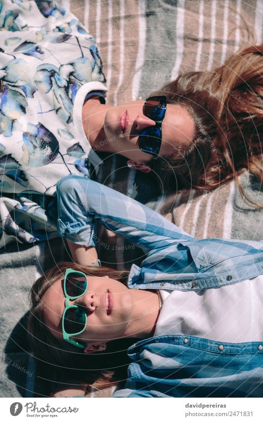 Two women with sunglasses lying taking a sunbath Lifestyle Joy Happy Beautiful Relaxation Leisure and hobbies Summer Sun Sunbathing Camera Human being Woman