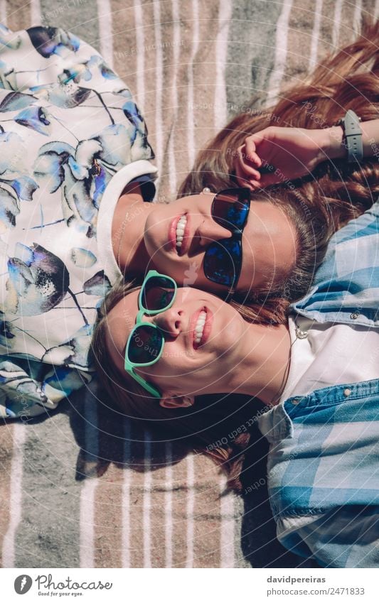 Two women with sunglasses smiling lying in blanket Lifestyle Joy Happy Beautiful Relaxation Leisure and hobbies Summer Sun Sunbathing Human being Woman Adults