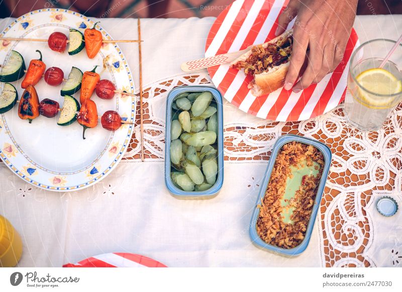 Male hand holding hot dog on red striped plate Sausage Bread Roll Lunch Fast food Lemonade Plate Lifestyle Joy Happy Summer Human being Man Adults Friendship