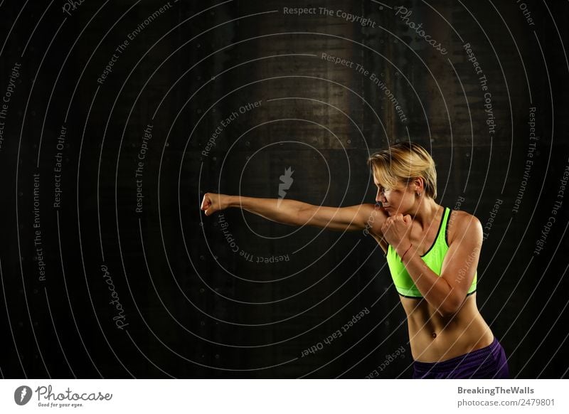 Close up side view profile portrait of one young athletic woman shadow boxing in sportswear in gym over dark background, looking away Lifestyle Sports Fitness