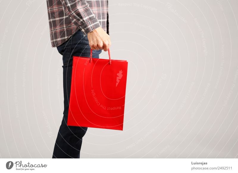 Man in jeans and plaid shirt with red bag in his hand Shopping Joy Valentine's Day Mother's Day Christmas & Advent Masculine Young man Youth (Young adults) Hand