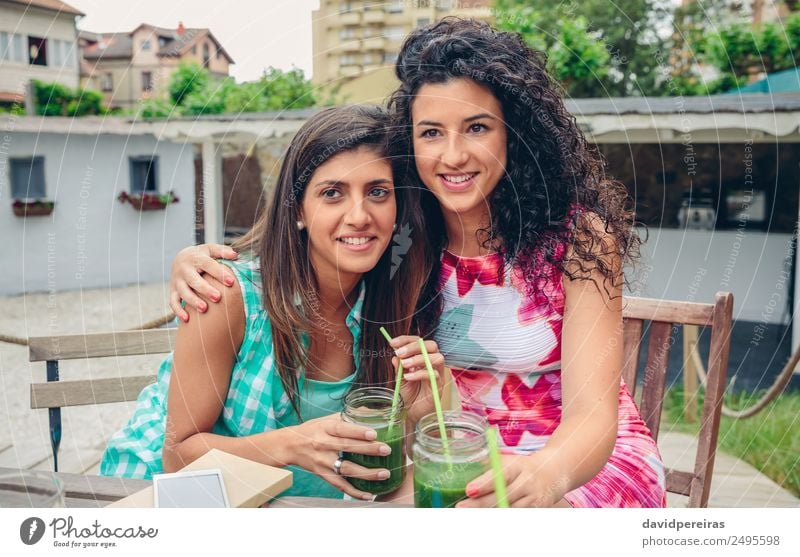 Two women embraced with smoothies looking at camera Vegetable Fruit Beverage Juice Lifestyle Joy Happy Leisure and hobbies Summer Human being Woman Adults