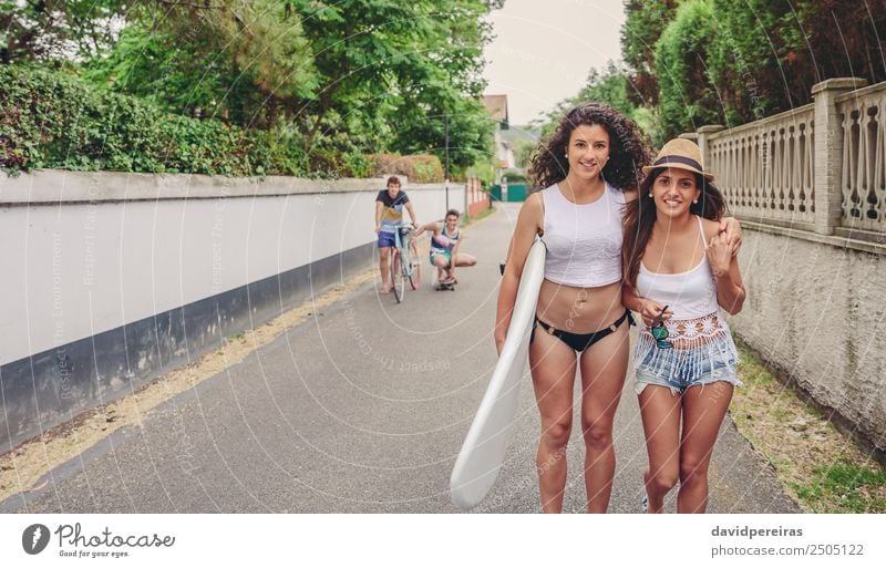 Two women holding surfboard and looking at camera Lifestyle Joy Happy Leisure and hobbies Summer Sports Woman Adults Man Friendship Youth (Young adults) Group