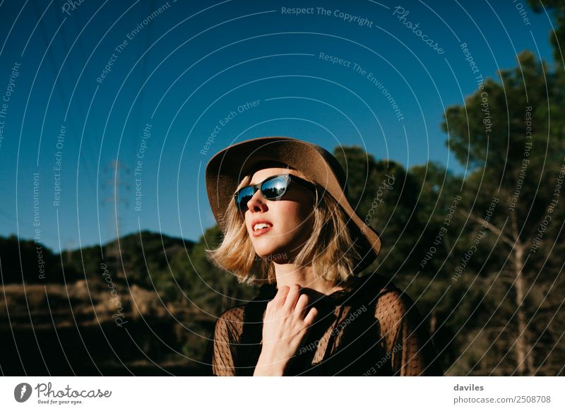 Cute blonde girl having a sunbath in nature wearing sunglasses and a hat Lifestyle Elegant Style Joy Wellness Relaxation Calm Vacation & Travel Freedom