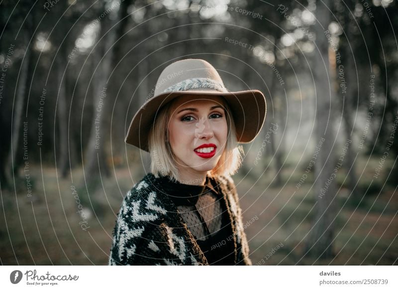 Portrait of smiling blonde woman with hat while she walks in nature looking into camera. Lifestyle Beautiful Vacation & Travel Tourism Trip Adventure Mountain