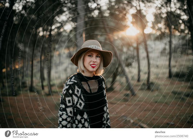 Blonde woman with hat taking a walk in the forest at sunset with the sun in the background. Lifestyle Joy Beautiful Vacation & Travel Tourism Trip Adventure