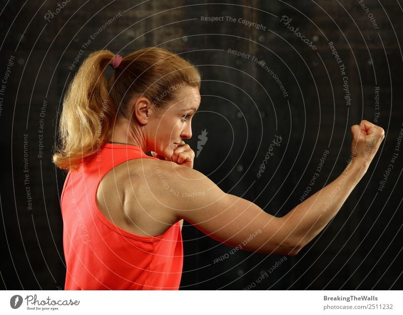 Close up side view profile portrait of one young middle age athletic woman shadow boxing in sportswear in gym over dark background, looking away Lifestyle