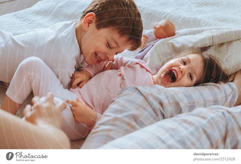 Relaxed mother and sons playing over the bed Lifestyle Joy Happy Beautiful Relaxation Leisure and hobbies Playing Bedroom Child Baby Boy (child) Woman Adults