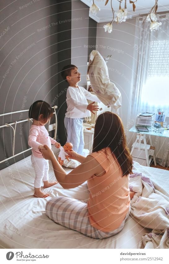 Relaxed mother and sons playing over the bed Lifestyle Joy Happy Beautiful Relaxation Leisure and hobbies Playing Bedroom Child Baby Boy (child) Woman Adults