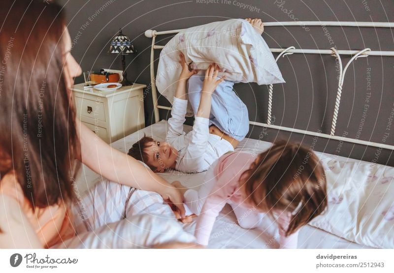 Relaxed mother and sons playing over the bed Lifestyle Joy Happy Beautiful Relaxation Leisure and hobbies Playing Bedroom Child Baby Boy (child) Woman Adults